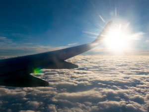 jet wing over clouds with sun